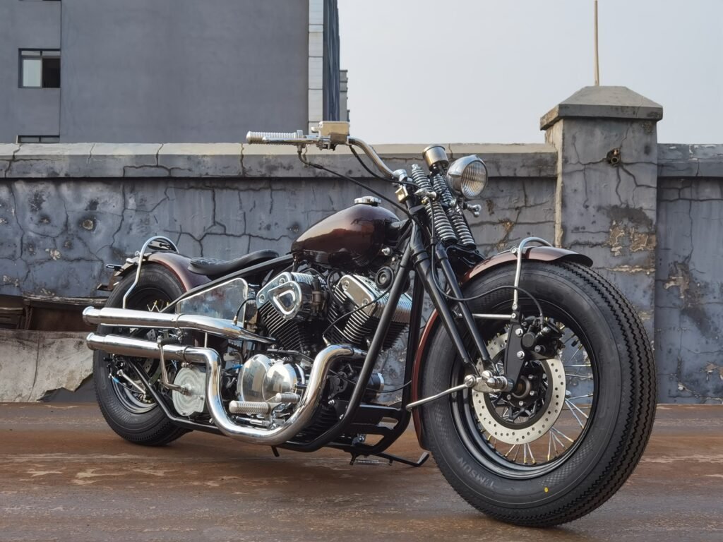 Black custom bobber motorcycle with springer front end, low solo seat and chrome dual exhaust in front three quarter view