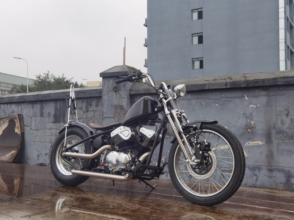 Black custom chopper motorcycle with tall sissy bar, springer front end, solo seat and chrome V twin engine on wet concrete surface