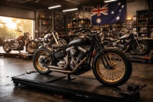Custom bobber motorcycle in an Australian workshop with other custom build projects in the background